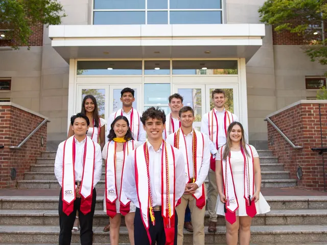 Graduating SCG members in white with red SCG stoles on the steps of a campus building.