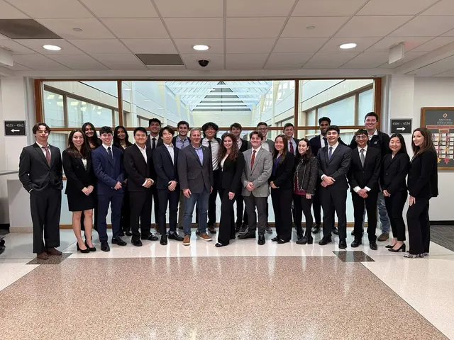 SCG members in business attire lined up in a wide building hallway under a skylight.