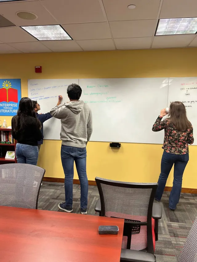Three members writing ideas on a large whiteboard in a meeting room.